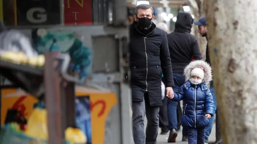 Un uomo cammina con la figlia per strada - Foto Ansa/Epa © www.giornaledibrescia.it