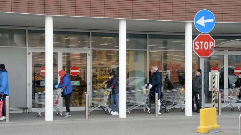 Persone in coda fuori dal supermercato