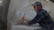 Angelo Confortini al lavoro su un blocco di marmo di Botticino - Foto © www.giornaledibrescia.it
