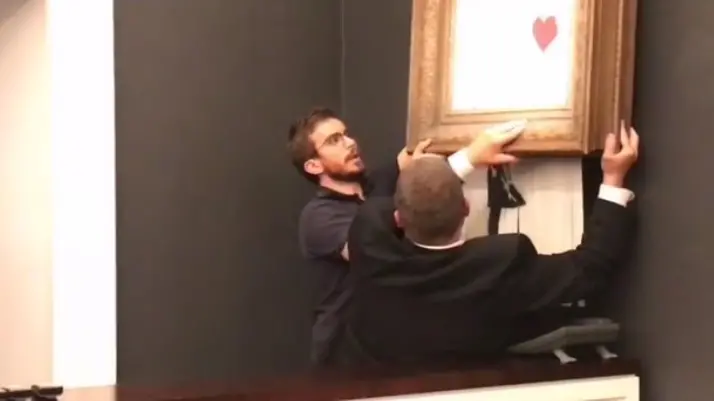 Gli addetti di Sotheby's rimuovono l'opera di Banksy