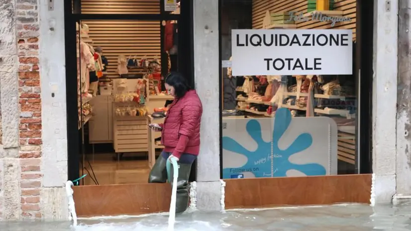 Una negoziante alle prese con l'acqua alta a Venezia - Foto Ansa/Emiliano Crespi © www.giornaledibrescia.it