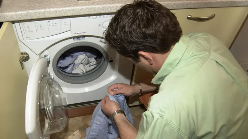 Un uomo mentre carica la lavatrice - Foto © www.giornaledibrescia.it