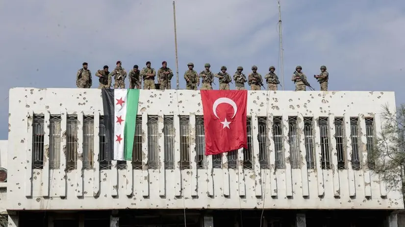 Soldati turchi e miliziani siriani appoggiati da Ankara su un palazzo nella città di Ras al Ayn - Foto Ansa/AP © www.giornaledibrescia.it