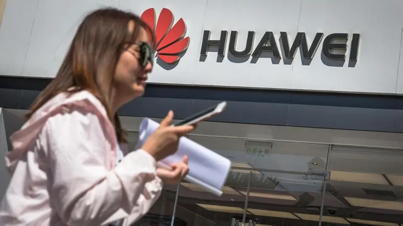 Una donna cammina fuori da un negozio Huawei a Pechino - Foto © www.giornaledibrescia.it