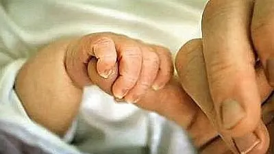Un neonato stringe la mano della mamma