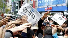 Dopo l'annuncio in tv, ressa per aggiudicarsi una copia dei quotidiani che riportano la notizia - Foto Koji Sasahara per Ap/Ansa