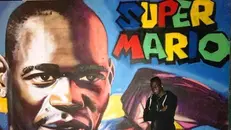 Il 17enne arrivato dal Gambia fino a Brescia davanti ad un murale dedicato a Mario Balotelli - © www.giornaledibrescia.it
