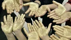 Le mani colorate d’oro dei ragazzi - © www.giornaledibrescia.it