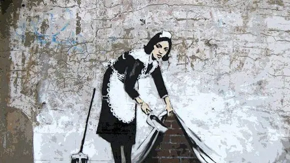 L’attuale condizione del pianeta si riassume nell’opera murale di Banksy, dove l’artista -writer ha rappresentato una cameriera che spazza la polvere sotto il tappeto - Foto di repertorio