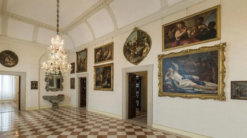 La Galleria. Il grande ambiente d’accesso alle sale, con alcuni dipinti della collezione e uno dei preziosi lampadari in vetro di Murano