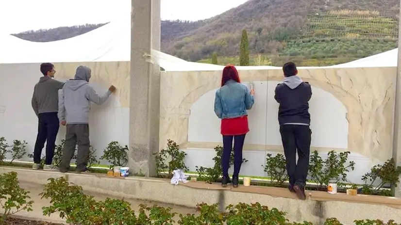 Gli immigrati preparano il fondo per i murali, i liceali trasferiscono i disegni e realizzano l’opera