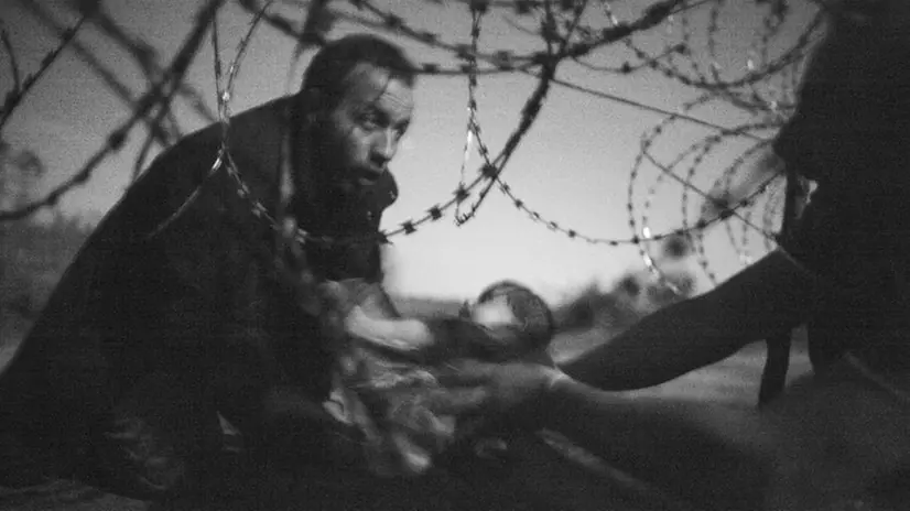 Un uomo passa un bambino attraverso la recinzione tra Ungheria e Serbia a Röszke, Ungheria, 28 agosto 2015 © Warren Richardson, Australia