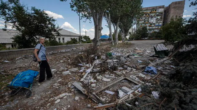 epa10068293 A picture taken during a visit to Lysychansk organised by the Russian military shows local woman carries humanitarian aid through debris in downtown of Lysychansk, Luhansk region, Ukraine, 12 July 2022 (issued 13 July 2022). Russian Defense Minister Shoigu on 04 July 2022 reported to Russian President Putin that the Russian Armed Forces and the People's Militia of the self-proclaimed Luhansk People's Republic (LPR) established full control over the territories of the self-proclaimed LPR within the administrative boundaries of the Luhansk region. According to Shoigu, the losses of the Armed Forces of Ukraine over the past two weeks in the battles for Severodonetsk and Lisichansk amounted to almost 5,500 people. On 24 February 2022 Russian troops entered the Ukrainian territory in what the Russian president declared a 'Special Military Operation', starting an armed conflict that has provoked destruction and a humanitarian crisis. EPA/SERGEI ILNITSKY