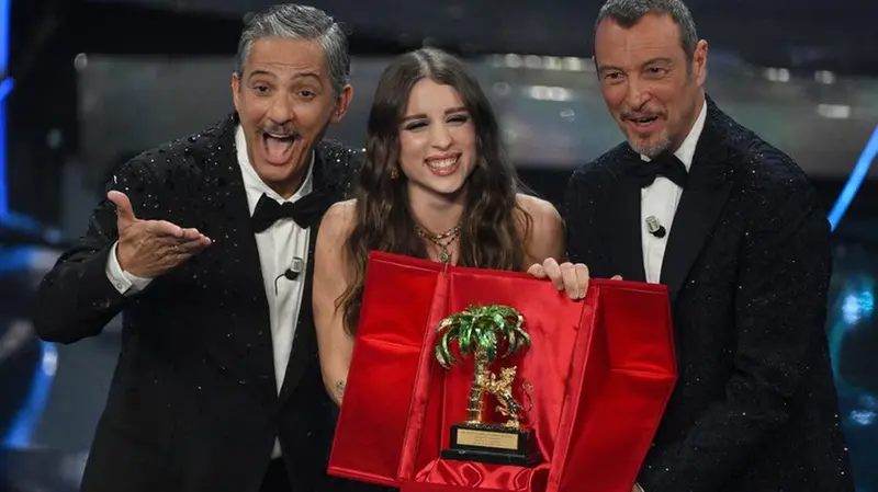 Italian singer Angelina Mango (C) poses with the trophy together with Sanremo Festival co-host and showman Rosario Fiorello (L) and Sanremo Festival host and artistic director Amadeus (R) after winning the Sanremo Italian Song Festival at the Ariston theatre during the 74th Sanremo Italian Song Festival, Sanremo, Italy, 10 February 2024. The music festival will run from 06 to 10 February 2024. ANSA/ETTORE FERRARI