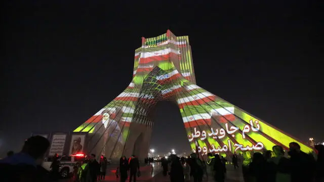epa11143143 Azadi (Freedom) tower is illuminated with pictures of Iranian late supreme leader Ayatollah Ruhollah Khomeini and Iran's national flag during a ceremony organized by the city municipality ahead of the 45th anniversary of the Islamic Revolution, in Tehran, Iran, 10 February 2024. Iran will celebrate its 45th revolution anniversary on 11 February 2024.  EPA/ABEDIN TAHERKENAREH
