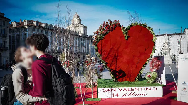 Due ragazzi si baciano davanti all'installazione dell'associazione fiorai che rappresenta un grande cuore fatto di fiore per la festa di San Valentino in piazza Castello, Torino, 03 febbraio 2023. ANSA/TINO ROMANO