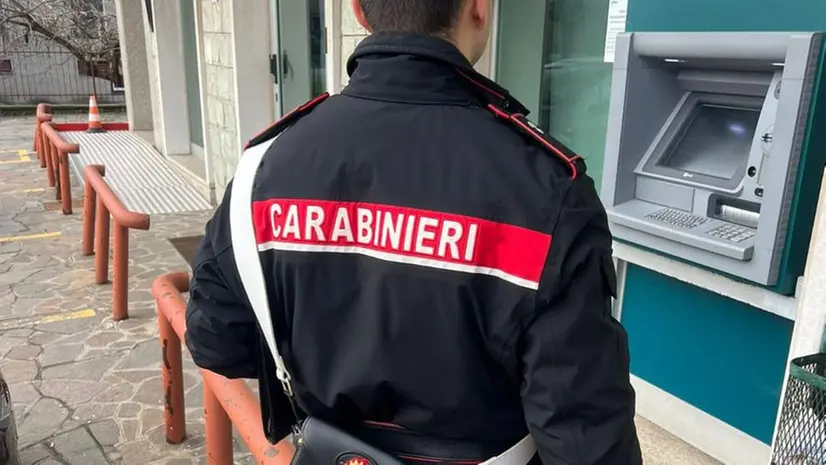 Un carabiniere davanti a uno sportello del bancomat