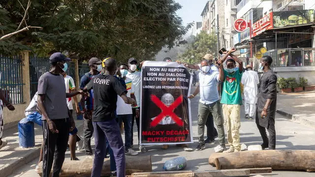 epa11140273 Protesters display a banner that reads 'Macky, putschist, get out' during a protest in Dakar, Senegal, 09 February 2024. Members of the civil and religious societies have demanded the restoration of the Republican calendar after Senegal's President Macky Sall postponed the presidential elections, originally scheduled for 25 February 2024, to 15 December 2024. On 05 February 2024, pro-government lawmakers passed a bill to extend Sall's tenure by 10 months and delayed the elections with just three weeks to go.  EPA/JEROME FAVRE