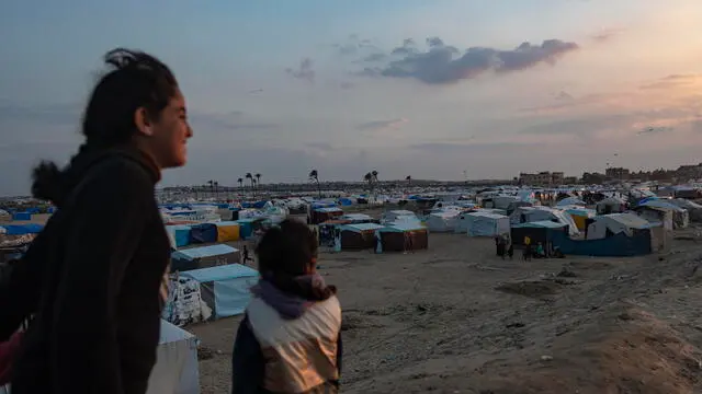 epa11159400 Palestinian on the beach at sunset in front of the tents of internally displaced Palestinians in the Rafah refugee camp, southern Gaza Strip, 16 February 2024. Since 07 October 2023, up to 1.9 million people, or more than 85 percent of the population, have been displaced throughout the Gaza Strip, some more than once, according to the United Nations Relief and Works Agency for Palestine Refugees in the Near East (UNRWA), which added that most civilians in Gaza are in 'desperate need of humanitarian assistance and protection'. EPA/HAITHAM IMAD