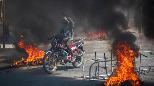 epaselect epa11192522 A person rides a motorcycle through street fires, in Port-au-Prince, Haiti, 01 March 2024, a day after gang violence left at least five dead and twenty injured. According to the latest report from the Haitian Police Union, there are five officers who died on 29 February and whose bodies have not yet been recovered. Initially, it was reported that four police officers lost their lives when armed gangs attacked a police station in Bon Repos, in Canaan, in the north of the capital. EPA/Johnson Sabin