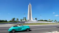 epa10730856 A classic car with tourists passes in front of the Plaza de la Revolucion in Havana, Cuba, 06 July 2023. The observation deck of the monument to Jose Marti in the Plaza de la Revolucion in Havana has reopened its doors to tourists after being closed for maintenance. From the highest point of the city, more than 150 meters above the ground, the viewpoint offers some of the best views of the Cuban capital. EPA/Ernesto Mastrascusa