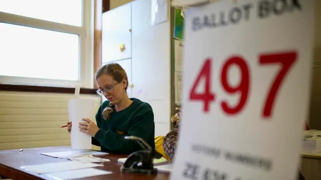 epa11206423 A polling clerk at a polling station as Ireland holds referenda on proposed changes to the wording of the Constitution on International Women's Day in Dublin, Ireland, 08 March 2024. The proposed changes relate to the areas of family and care. The family amendment proposes to extend constitutional protection to both married and other 'durable' relationships. The care amendment proposes removing references to a woman's roles and duties in the home, and replacing it with a new article that acknowledges family carers. EPA/MOSTAFA DARWISH