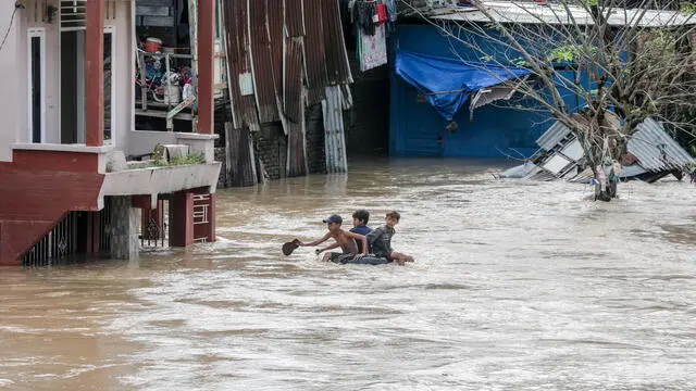 epa08863147 Boys ride on a tube through a flooded residential area in Medan, North Sumatra, Indonesia, 05 December 2020. At least five people died as heavy rains flooded thousands of homes, according to the National Board for Disaster Management (BNPB). EPA/DEDI SINUHAJI