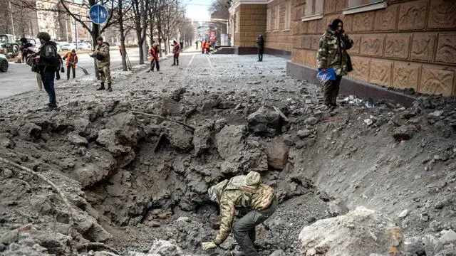 epa11168094 Russian Investigator examines a shelling crater in the aftermath of a shelling in downtown Donetsk, Russian-controlled Ukraine, 20 February 2024. A woman was killed and dozens were injured in the shelling of Kievsky and Voroshilovsky districts of Donetsk, according to city Mayor Alexey Kulemzin. EPA/VALERY MELNIKOV