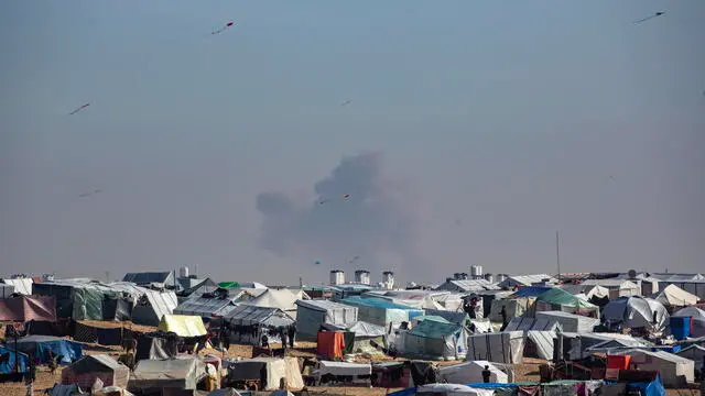 epa11136395 A camp of internally displaced Palestinians at the Gaza border with Egypt, while smoke rises from an Israeli air strike, in the Rafah refugee camp, southern Gaza Strip, 08 February 2024. Since 07 October 2023, up to 1.9 million people, or more than 85 percent of the population, have been displaced throughout the Gaza Strip, some more than once, according to the United Nations Relief and Works Agency for Palestine Refugees in the Near East (UNRWA), which added that most civilians in Gaza are in 'desperate need of humanitarian assistance and protection'. EPA/HAITHAM IMAD