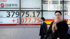 epa11149126 Passersby walk past a Tokyo stock market indicator board in Tokyo, Japan, 13 February 2024. Tokyo stock market soared gaining more the 1,000 points to reach a new 34-year high. The 225-issue Nikkei Stock Average closed up 2.89 percent at 37,963.97, its highest since January 1990. EPA/FRANCK ROBICHON