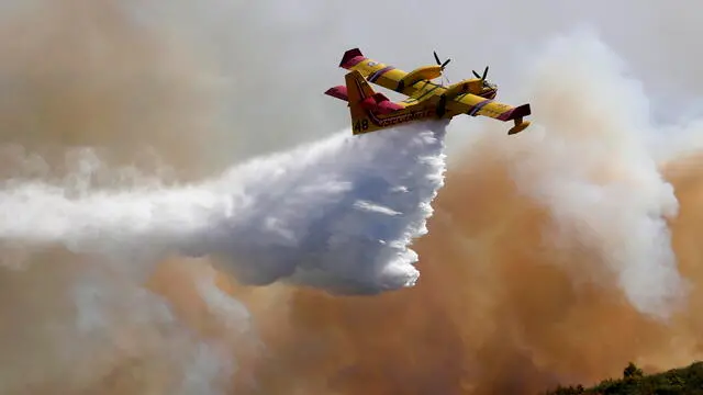 epa10092573 A Canadair plane drops water on a forest fire near the city of Gignac, France, 26 July 2022. 700 hectares have been burnt and 200 people were evacuated from the village of Aumelas. EPA/Guillaume Horcajuelo