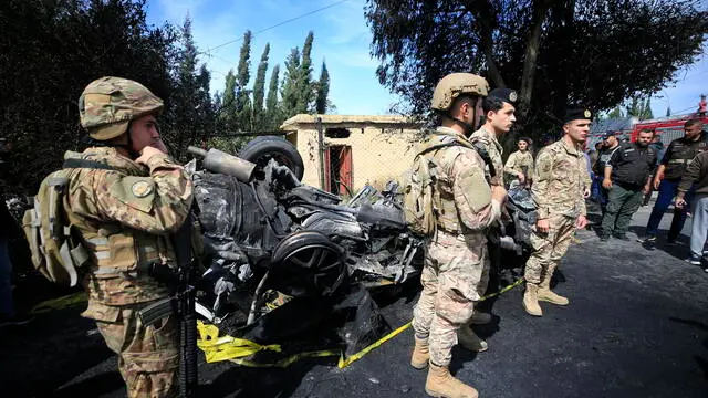 epa11218113 Lebanese army soldiers stand around a wrecked car targeted by an Israeli drone on Al Hoash Road, near the coastal city of Tyre, southern Lebanon, 13 March 2024. Lebanese state media said at least two were killed including a Palestinian inside the car which was targeted by an Israeli drone and a Syrian national who was riding a motorcycle at the site of the attack. Israel Defense Forces (IDF) said an aircraft in the area of Tyre struck Hadi Ali Mustafa, a significant operative in Hamas' department responsible for attacks against Israeli and Jewish targets around the world. EPA/STR