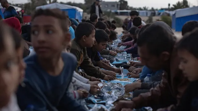 epa11247142 Displaced people sit together next to their tents to eat during the holy month of Ramadan at a collective Iftar meal organized by a youth volunteer group in the Rafah camp in the southern Gaza Strip, 27 March 2024. The Muslims' holy month of Ramadan is the ninth month in the Islamic calendar and it is believed that the revelation of the first verse in the Koran was during its last 10 nights. It is celebrated yearly by praying during the night time and abstaining from eating, drinking, and sexual acts during the period between sunrise and sunset. It is also a time for socializing, mainly in the evening after breaking the fast and a shift of all activities to late in the day in most countries. EPA/HAITHAM IMAD