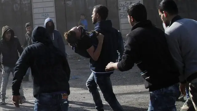 epa05144669 Palestinian protesters carry a wounded man after he was hit by a shot fired from Israeli soldiers during clashes at the West Bank village of Qabatiya, near Jenin, 05 February 2016. The clashes erupted between Palestinian residents and the Israeli military 05 February, a day after forces raided the northern West Bank hometown of three militants who had launched a shooting and stabbing attack in Jerusalem the previous day. Israeli military closed off roadblocks and checkpoints in and out of the town while soldiers prepared punitive measures to raze the homes of the three attackers. At least four Palestinians were injured, including a 16-year-old boy who was hit by a military vehicle, the mayor of the town of Qabatiya, Mahmoud Kmeil, said. EPA/ALAA BADARNEH