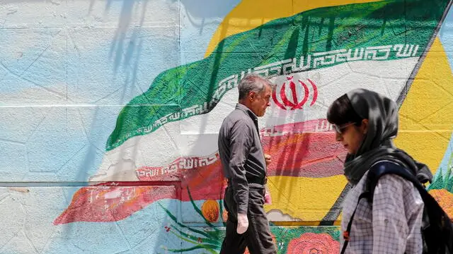 epa10686669 Iranians walk next to a street wall painting of Iran's national flag in Tehran, Iran, 12 June 2023. Iran's Supreme Leader Ali Khamenei said on 11 June during a meeting with Iranian nuclear scientists, that the West could not stop Iran's nuclear progress, as he urged continued cooperation with the International Atomic Energy Agency (IAEA), amidst the scrutiny from Western powers on the country's nuclear programme. EPA/ABEDIN TAHERKENAREH