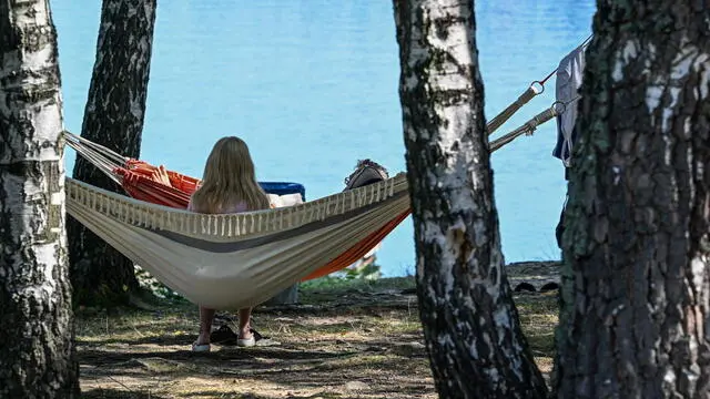 epa10807585 People sit in hammocks as they enjoy the weather at Solinskie Lake in Polanczyk, south-eastern Poland, 19 August 2023. People enjoy the warm temperatures and bright sunshine at a beach in the Lake Solina resort of Polanczyk. Temperatures rose to up to 34 degrees Celsius. EPA/DAREK DELMANOWICZ POLAND OUT