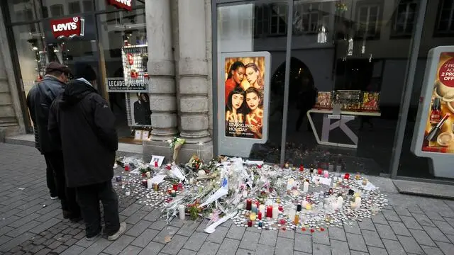 epa07230471 People look at candles, letters and flowers at a place close to the Christmas Market, in Strasbourg, France, 14 December 2018, where a terror attack took place. Cherif Chekatt, the perpetrator of the Christmas Market attack, has been killed, at a building rue de Lazaret, in the Neudorf district of Strasbourg, on 13 December 2018. Three people died following the shooting at the market and several more were seriously injured during the incident on 11 December 2018. EPA/RONALD WITTEK