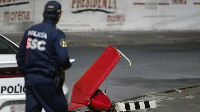 epa11279321 A police officer stands near a part of the tail of the helicopter that crashed at a automotive workshop, in CoyoacÃ¡n, Mexico City, Mexico, 14 April 2024. Three deaths, presumably the pilot and two crew members, were caused by the fall of a private helicopter in the CoyoacÃ¡n neighborhood south of Mexico City, capital government authorities reported. EPA/Isaac Esquivel