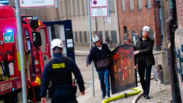 epa11281350 Locals carry a painting from the old Stock Exchange (Boersen) after a fire hit the building, in Copenhagen, Denmark, 16 April 2024. A violent fire broke out in the building which is under renovation on the morning of 16 April. The building was erected in the 1620s as a commercial building by King Christian IV and is located next to the Danish parliament. EPA/Ida Marie Odgaard DENMARK OUT