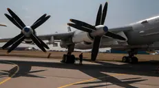 epa09354617 A pilot stands in the shadow of the Tupolev Tu-95 turboprop-powered strategic bomber at the MAKS 2021 International Aviation and Space Salon in Zhukovsky outside Moscow, Russia, 20 July 2021. The International Aviation and Space Salon MAKS 2021 take place from 20 to 25 July. EPA/SERGEI ILNITSKY