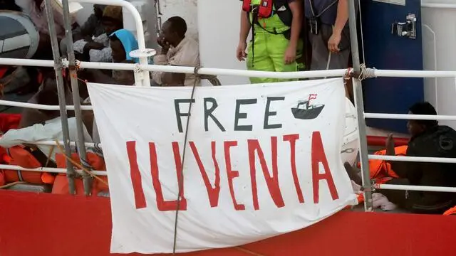 epa06845931 'Free Iuventa' on a sign as migrants on board the Lifeline NGO rescue vessel stranded in the Mediterranean with more than 200 migrants finally berthed in Valletta, Malta, on 27 June 2018. EPA/DOMENIC AQUILINA