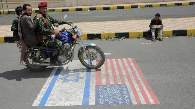 epa11288837 Houthi supporters ride a motorcycle over US and Israeli flags on the ground during a protest against the US and Israel, and in solidarity with the Palestinians, in Sana'a, Yemen, 19 April 2024. Thousands of Houthi supporters participated in a protest against the United States and Israel and to show their solidarity with the Palestinians of Gaza amid the ongoing conflict between Israel and Hamas. The protest came just a day after the Houthis' top leader, Abdul-Malik al-Houthi, claimed his group had launched some 14 drone and missile attacks against shipping lanes in the Red Sea and the Gulf of Aden and towards the southern Israeli port of Eilat in the last two weeks in support of the Palestinian people in the Gaza Strip. EPA/HAMZA ALI