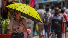 epa10576847 A woman walks with her umbrella to avoid the heat wave on a hot afternoon in Mumbai, India, 17 April 2023. India Meteorological Department (IMD) issued a heat wave warning to several parts of India. EPA/DIVYAKANT SOLANKI