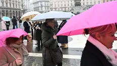 Persone camminano in piazza Duomo indosssando giacche invernali e proteggendosi dalla pioggia con ombrelli, Milano, 22 febbraio 2024. Sono in arrivo 5 giorni di maltempo, con piogge e vento forte. Previste anche abbondanti nevicate sulle Alpi dove cadrà oltre un metro di neve. ANSA/DANILE DAL ZENNARO