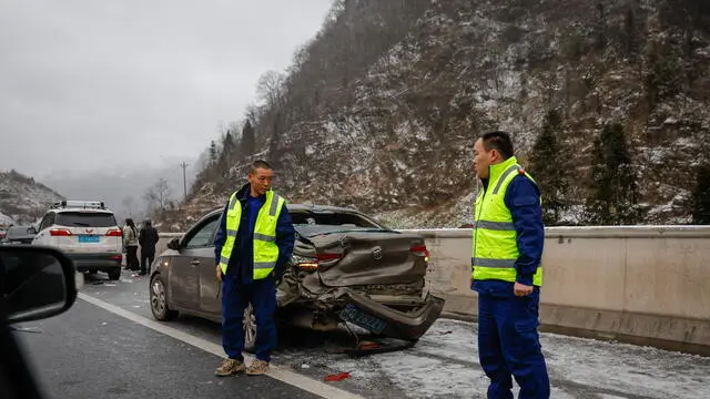 epa11100713 Local security stand guard at a damaged car following an accident caused by slippery roads in Zhenxiong County, Yunnan province southwest of China, 24 January 2024. Local authorities reported at least 31 dead and more than 10 people missing after a landslide hit Liangshui Village in China's southwest province of Yunnan early morning on 22 January. Over 1,000 personnel have been mobilized by the government to help in rescue and evacuation efforts. EPA/MARK R. CRISTINO