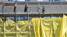 Operai edili al lavoro sulla facciata di uno stabile di Milano, 6 settembre 2023. ANSA/DANIEL DAL ZENNARO