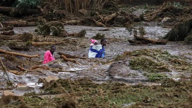 epa11308906 A woman carries a baby as she makes her way in an area affected after Old Kijabe Dam burst its banks and caused flash floods through several villages in Mai Mahiu, in the Rift Valley region of Naivasha, Kenya, 29 April 2024. The flash floods left behind a trail of damaged houses that got swept away, claiming 42 death so far as search and rescue mission continues, according to Kenya Red Cross Society. Kenya and the wider East African region continue to experience flooding due to the ongoing heavy rainfall. EPA/DANIEL IRUNGU