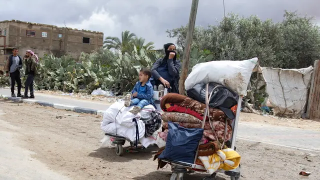 epa11321291 An Internally displaced Palestinian woman and child with their belongings at a street after an evacuation order issued by the Israeli army, in Rafah, southern Gaza Strip, 06 May 2024. The Israeli military stated on 06 May that the IDF has called on the residents of eastern Rafah to 'temporarily' evacuate to an expanded humanitarian area. The statement came ahead of an expected Israeli offensive on the city. More than 34,600 Palestinians and over 1,455 Israelis have been killed, according to the Palestinian Health Ministry and the Israel Defense Forces (IDF), since Hamas militants launched an attack against Israel from the Gaza Strip on 07 October 2023, and the Israeli operations in Gaza and the West Bank which followed it. EPA/HAITHAM IMAD