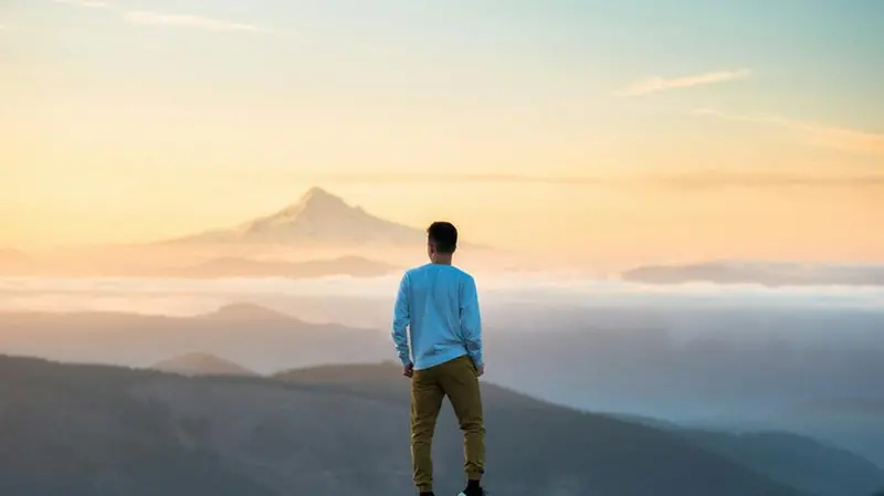 Un ragazzo guarda l'orizzonte in montagna - Foto Unsplash