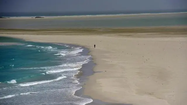 epa03638064 A picture made available 23 March 2013 shows a Yemeni fisherman walking on white sands on the shore of the island of Socotra, in the Indian Ocean, Yemen, 14 March 2013. The island of Socotra is situated in the Indian Ocean, some 250 miles off the coast of Yemen. It is the largest island in the Middle East and is known to the world as one of the best sites to witness biodiversity. During the monsoon season, which lasts from late May until late September each year, extremely high winds blow white sand dunes from Socotra's beautiful unspoiled beaches into nearby escarpments and hills. EPA/YAHYA ARHAB